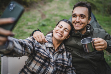 happy couple campers take a self portrait or video call in front tent