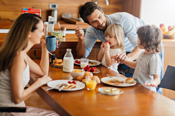 Happy family enjoying breakfast together in modern kitchen