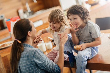 Mother having fun with her kids in the kitchen during breakfast