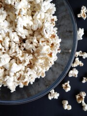 Salted popcorn close up in a bowl on a dark background. Movie night with popcorn. Cinema and entertainment concept. Salty snack