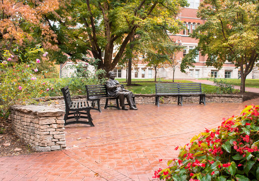 Indiana University, Bloomington, IN - USA: Statue of seated Herman B. Wells on bench in beautiful garden setting, early fall. Old Crescent area near the Rose Wellhouse. 