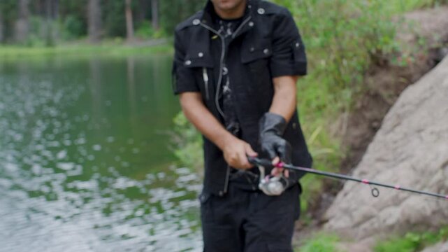 Man casting out fishing line into lake - steady cam, medium shot