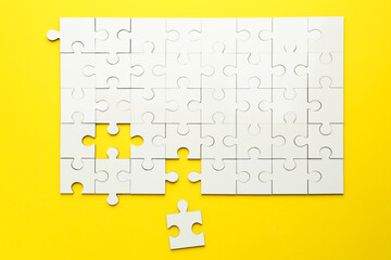 White puzzle pieces on yellow background, top view