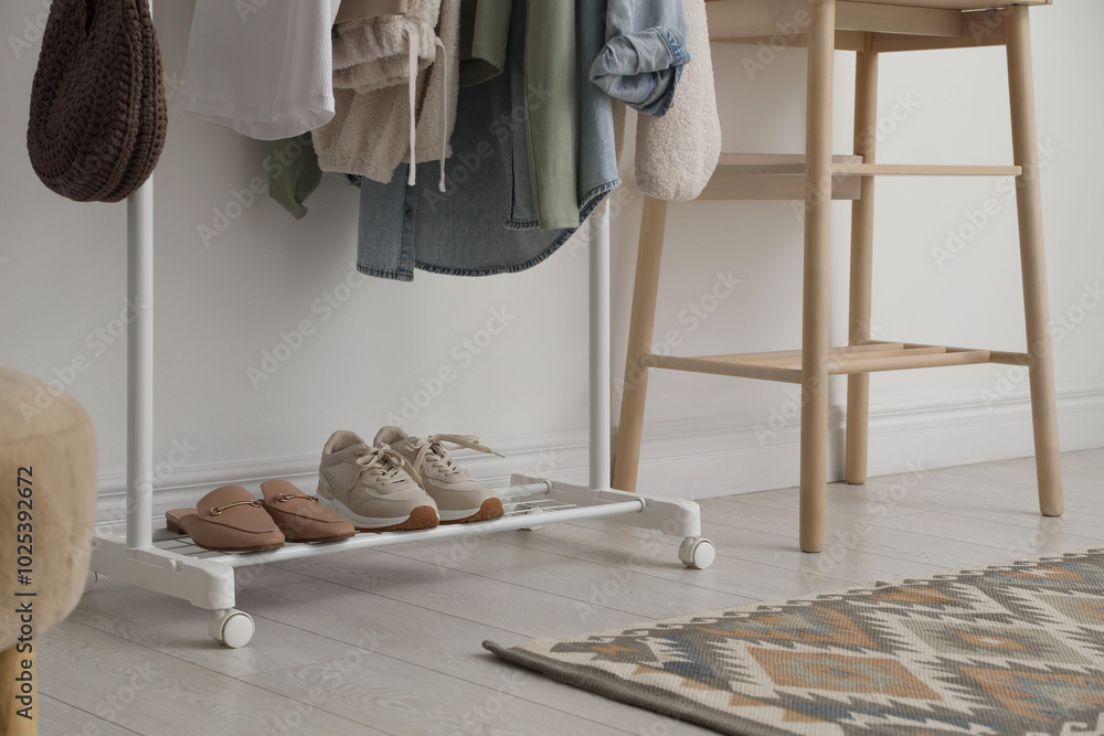 Wall mural Rack with clothes, shoes and standing desk near white wall