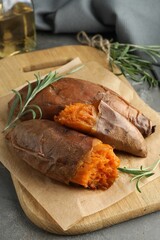 Tasty cooked sweet potatoes served with rosemary on grey table, closeup