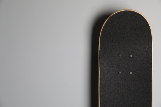 Modern skateboard on light grey background. Space for text
