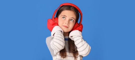 Little girl listening to music on blue background