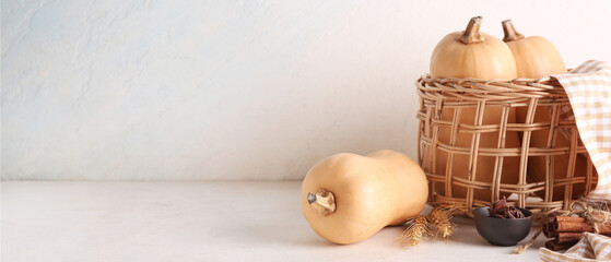 Wicker bowl with fresh pumpkins, wheat, cinnamon and star anise on white background