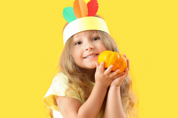 Cute little girl with pumpkin on yellow background, closeup. Thanksgiving Day celebration