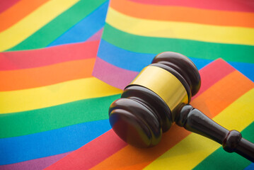 Close up judge wood gavel hammer on colorful rainbow LGBT pride flag background. Legal status of same-sex marriage, LGBT human rights, equality and freedom concept. © pla2na