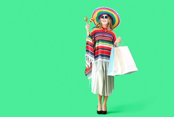 Young woman with painted skull, maracas and shopping bags on green background. Mexico's Day of the Dead (El Dia de Muertos) celebration