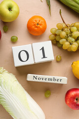 Calendar with date 1 November and different fresh fruits on beige background