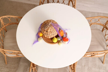 Dining table with Halloween pumpkins and basket in kitchen, top view