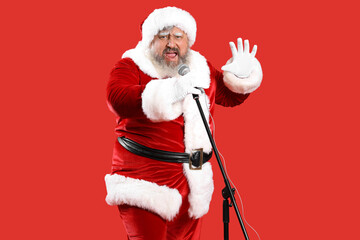 Cool Santa Claus with microphone singing Christmas song on red background