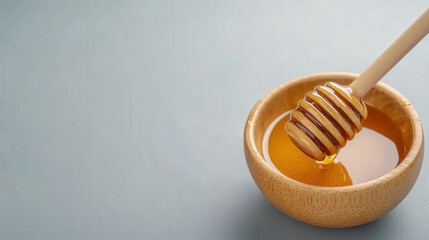 Honey Dipper in Wooden Bowl Filled with Fresh Honey on Minimalist Background