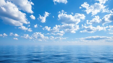 Obraz premium A vast expanse of blue ocean stretches out under a clear sky with scattered white clouds.