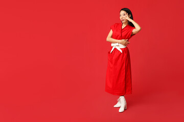 Beautiful young stylish Asian woman on red background. Chinese New Year celebration
