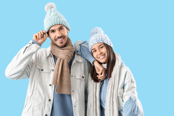 Loving couple in winter clothes on blue background