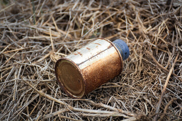 Used drink cans are rusty and thrown carelessly on the dry grass