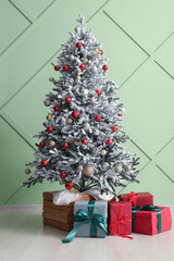 Christmas tree with beautiful gift boxes near color wall