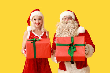 Happy Santa and MRS Claus with gift boxes on yellow background