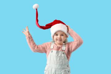 Cute little girl in Santa hat on blue background