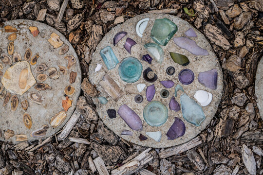 Concrete stepping stones decorated with colorful glass and stones on bark mulch ground