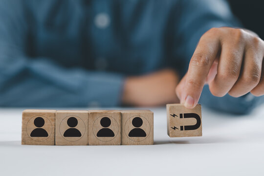 Customer retention concept. Inbound marketing strategy. Attracting potential customers. Hand puts wooden cubes with magnet attracts customer icons on beautiful grey background and copy space. Loyalty