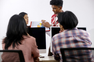 Group Of Asian Students Discussing Ideas And Collaborating On A School Project Together In Computer Classroom