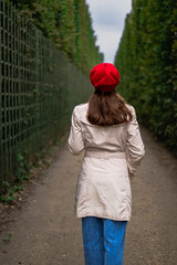 Girl in red beret walks in alley, back view