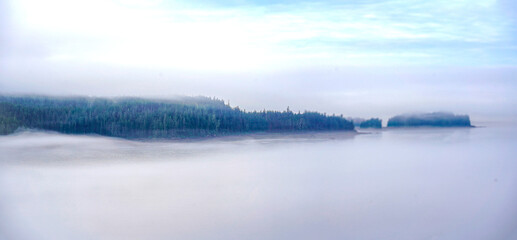 Panorama Islands and peninsula covered in wild spruce tree forest with mist and fog over the Pacific Ocean © Alexandra