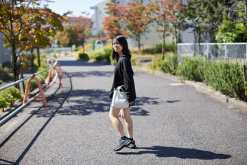 Fototapeta premium 秋の団地の敷地で歩く一人の高校生の姿