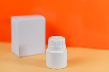White Plastic Bottle with Box on Orange Background