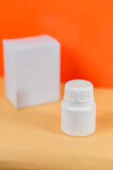 White Plastic Bottle and Box on Orange Background