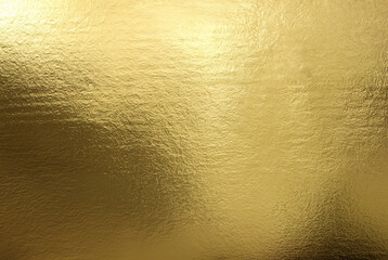 Shiny gold foil texture with a smooth, reflective surface ideal for backgrounds or luxurious...