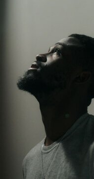 A bearded man in casual clothes leaned his head against the wall with a depressed look. Dim indoor lighting