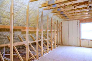 During home construction, thermal foam insulation is installed in ceiling of new frames for houses