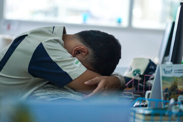 Salary man is sleeping on the desk after working hard. Officer is NAP in working time.
