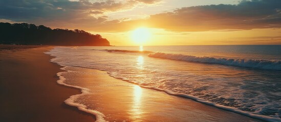 A scenic sunset on a sandy beach with waves crashing on the shore.