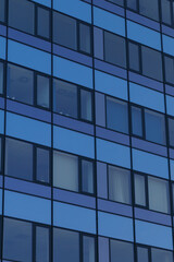 A close-up view of a modern building facade featuring a geometric pattern of blue panels with rectangular windows. 