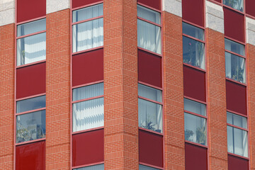 Close-up of a modern building facade featuring a geometric pattern of red brick columns and red panels.