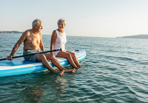 Senior couple enjoying paddleboarding on serene ocean adventure
