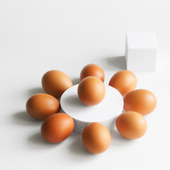 Nine chicken eggs next to white geometric shapes on white background. Healthy eating. Photo. Copy space