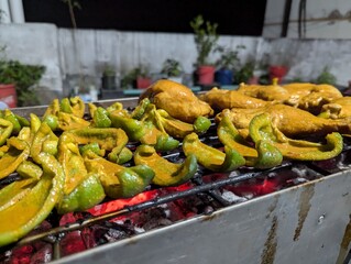 Grilling marinated chicken and vibrant peppers at a bustling outdoor barbecue event during a warm summer evening in a lively neighborhood garden
