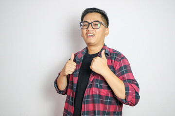 A happy Filipino man giving a rousing thumbs up in approval. In a white shirt and gray windbreaker. Isolated on a white backdrop.
