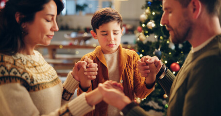 Family, praying and holding hands in home for Christmas, solidarity and gratitude with spiritual connection. Parents, boy and worship in living room for thanks, faith and vacation as Christian people