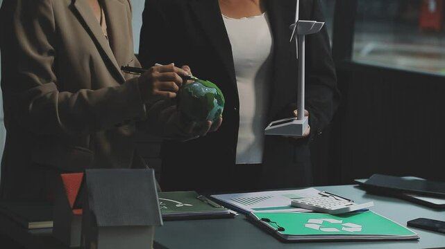 Business people having consultation about wind energy at company office. Business team discussing about windmill and alternative green enery. Net zero and carbon neutral concept