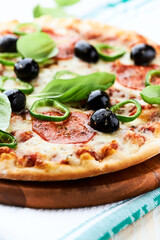 Pizza with salami, jalapeno pepper and black olives. Home made food. Concept for a tasty and hearty meal. Close up