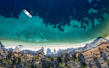 Tourists enjoying summer sunbathing and swimming on secluded beach drone aerial view. Kefalonia Island, Ionian Sea, Greece