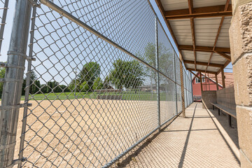 View from inside a baseball dugout with chain-link fencing
